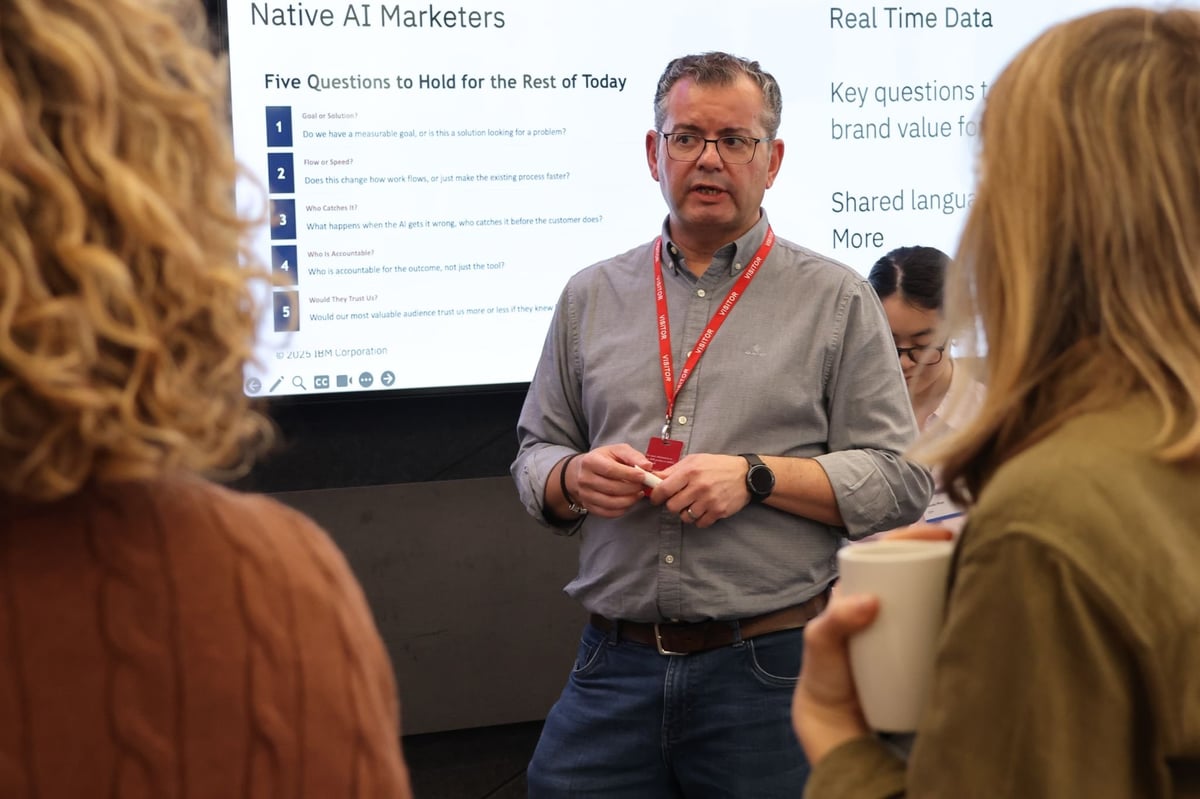Man with glasses and red badge presents to audience about Native AI Marketers and Real Time Data on screen behind him